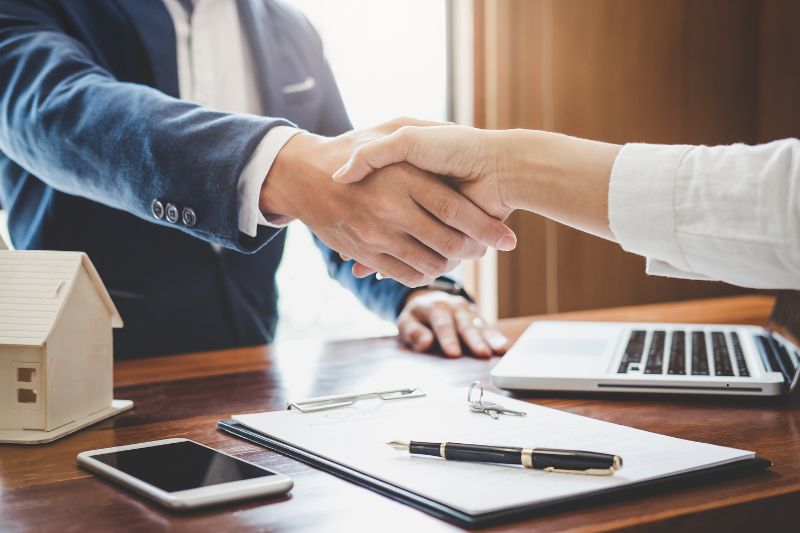 dettaglio di stratta di mani dopo aver firmato un contratto assicurativo