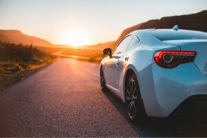 Auto parcheggiata su una strada al tramonto, simbolo di libertà e viaggio in sicurezza.