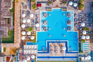 Vista dall’alto di una piscina di hotel con area relax, ombrelloni e lettini, simbolo di vacanze e soggiorni convenzionati.