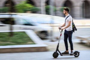 Uomo in monopattino elettrico in città, simbolo delle nuove regole su assicurazione RCA, casco e circolazione sicura.