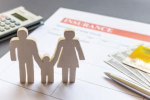 Sagome di una famiglia accanto a una polizza assicurativa, banconote e calcolatrice, simbolo di protezione economica e tutela familiare.