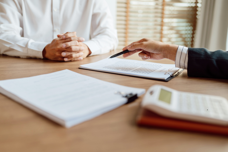 Consulente assicurativo illustra un documento a un cliente durante un incontro, per valutare le coperture contro gli infortuni extra-professionali.
